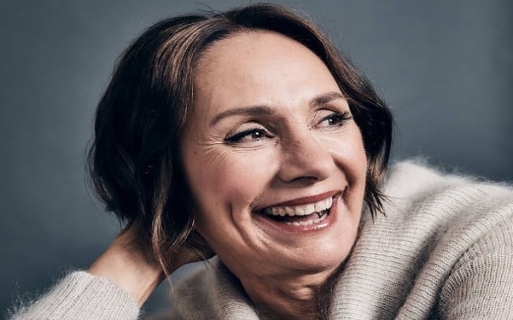 Laurie Metcalf smiling profusely in grey cardigan.